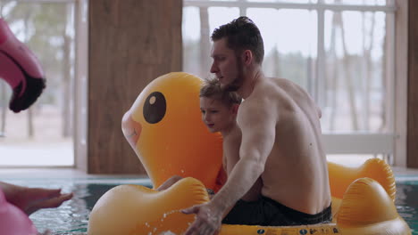 family-is-spending-weekend-in-water-park-father-and-son-are-riding-inflatable-duck-and-splashing-water